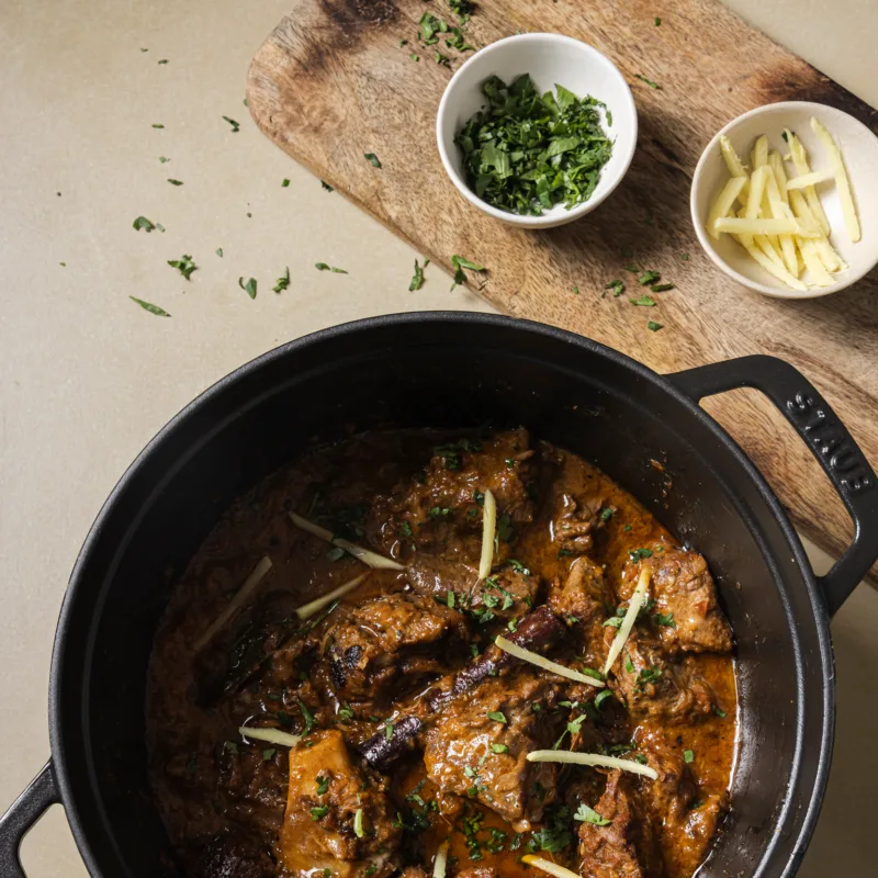 Pakistanisches Lamm Curry im Gusstopf, garniert mit Ingwer und Koriander